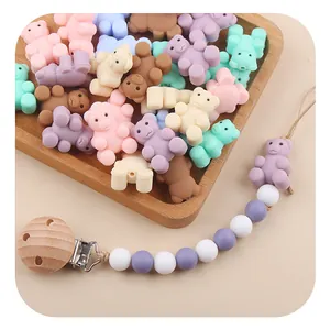 Detailed view of macaron colored silicone bear beads and pacifier clip on a wooden tray