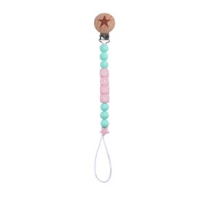 Detail of pink and mint silicone beads on a wooden pacifier clip with star and BABY text