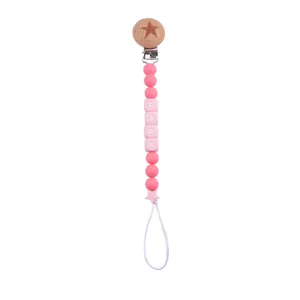 Detail of pink silicone beads and wooden clip with star carving on baby pacifier chain