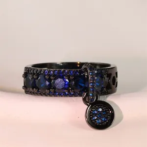 Détail de la bague gothique en métal noir avec zircons bleus et breloque circulaire