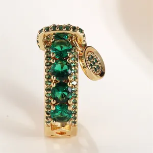 Vue macro détaillée d'un pendentif en or avec pierres précieuses vert émeraude et breloque