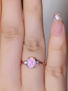 Dettaglio di un anello in oro rosa con una grande opale ovale dai riflessi rosa e viola
