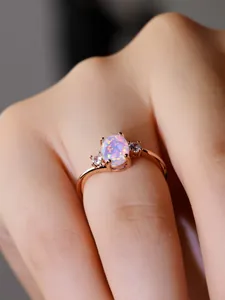 Anello in oro rosa con opale ovale e tre pietre indossato sulla mano di una donna