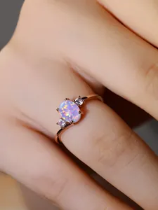 Dettaglio di un anello in oro rosa con grande opale ovale e due diamanti bianchi