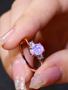 Dettaglio anello in oro rosa con opale blu ovale e zirconi bianchi sui lati