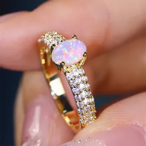 Luxurious gold ring featuring a large oval white opal and triple-row diamond band