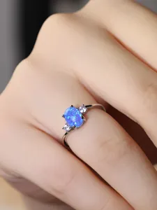 Dettaglio di un anello in argento con opale blu ovale e diamanti d'accento laterali