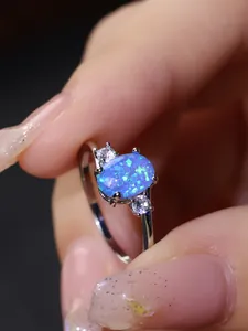 Dettaglio macro di un anello con opale blu ovale e due diamanti laterali in argento