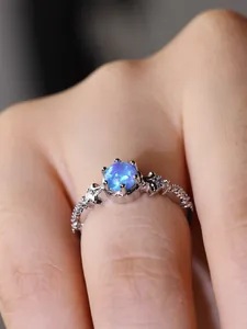 Nahaufnahme eines Vintage-Silberrings mit rundem blauen Opal und buntem Farbenspiel