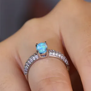 Detailed close-up of a silver ring with a round blue opal and pavé-set zircons on hand
