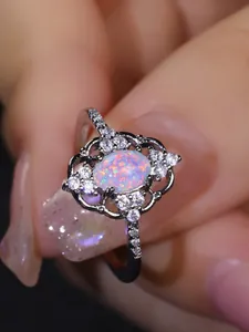 Primer plano de anillo con opalo ovalado, encaje calado vintage y cristales brillantes