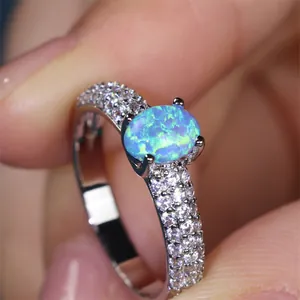 Macro shot of oval blue opal ring with pave-set sparkling zircons on silver band