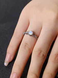 Detailansicht eines verzierten silbernen Vintage-Rings mit rundem weißem Opal und Steinen