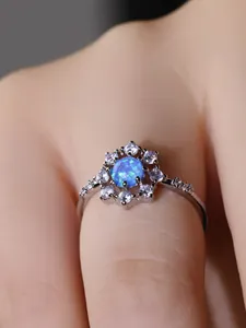 Dettaglio macro dell'anello con opale blu a forma di fiocco e pavé di zirconi bianchi