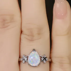 Macro shot of a teardrop opal flower ring with sparkling diamonds on a finger
