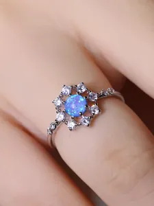 Dettaglio macro dell'anello in argento con opale blu rotondo e alone di zirconi bianchi