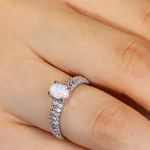Elegant white oval opal ring with zircon-encrusted silver band shown on a hand