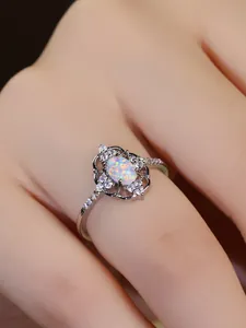 Detalle de anillo de ópalo ovalado con borde de encaje calado y acentos de circonitas blancas