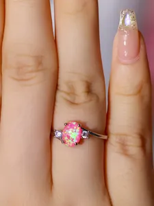 Dettaglio macro di un anello con opale rosa ovale e pietre laterali in argento