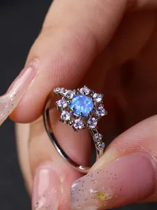 Dettaglio macro di anello in argento con opale blu rotondo e halo di diamanti micro-pavé