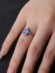 Vista detallada de un anillo de opalo azul ovalado con diseño de encaje de flores huecas