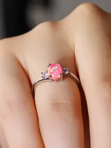 Dettaglio macro di un anello ovale con opale di fuoco rosa e zirconi bianchi su argento