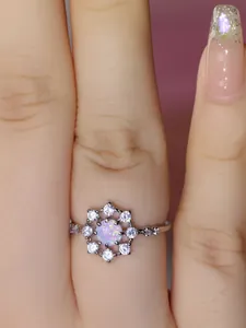 Vista macro di un anello a fiore in argento con opale rotondo e zirconi brillanti