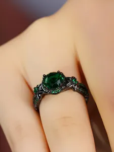 Detailed close-up of a vintage black metal ring featuring a large emerald green stone