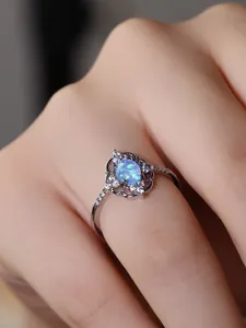 Detalle de anillo con opalo azul ovalado, encaje de plata y pequeñas piedras de circonio