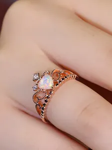 Close-up of rose gold crown ring with heart-shaped opal and delicate hollow detailing
