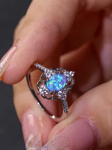 Detalle de anillo de plata con ópalo azul ovalado y halo floral de diamantes