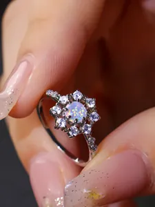 Vista macro di anello a girasole in argento con opale di fuoco tondo e zirconi scintillanti