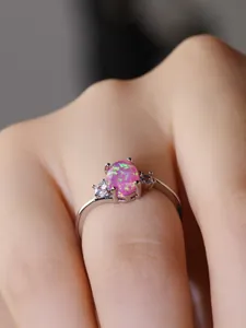 Primo piano di un anello d'argento con opale rosa ovale e due pietre laterali