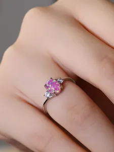 Dettaglio di un anello in argento con opale rosa ovale e pietre laterali bianche brillanti