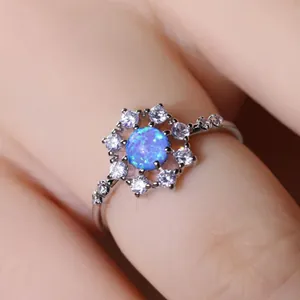 Anello a fiore in argento con opale blu e diamanti bianchi indossato al dito