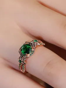Macro detail of rose gold vintage ring with oval emerald and floral leaf patterns