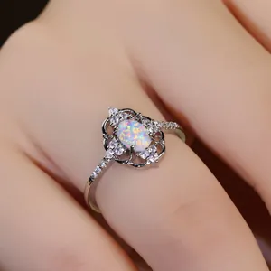 Anillo de ópalo ovalado con halo de diamantes y diseño vintage floral en mano