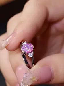 Vista macro di un anello con opale rosa ovale e diamanti laterali su fascia argento