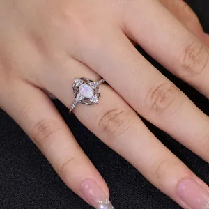 Anillo de ópalo ovalado con encaje de plata en un dedo sobre un fondo oscuro mate
