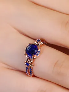Macro shot of a rose gold ring with a large oval blue sapphire and small pavé stones