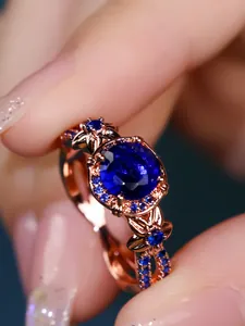 Macro shot of rose gold ring with large blue gemstone and floral side accents