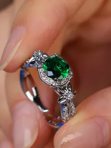 Macro detail of oval green gemstone ring with silver floral pattern and pavé diamonds