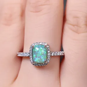 Dettaglio macro di anello con opale taglio cushion e halo di diamanti in argento