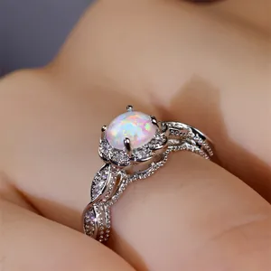 Makroaufnahme von Silberring mit ovalem weißem Opal, bunter Feuerung und Diamantspitze