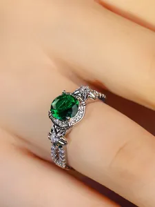 Macro shot of a silver ring featuring a large green gemstone and flower relief details