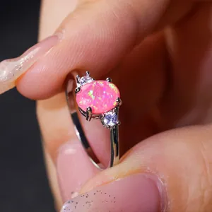 Elegante anello in oro bianco con opale rosa ovale e zirconi sulla mano di una modella