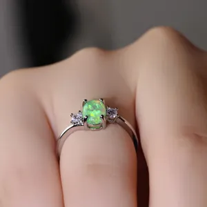 Anello elegante in argento con opale verde ovale e pietre su un dito