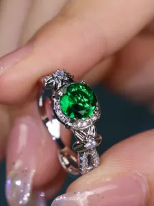 Macro shot of silver ring with green round zircon and intricate floral petal design