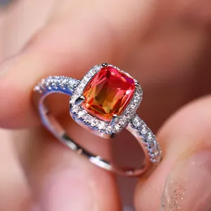 Macro detail of rectangle cut gradient gem ring with halo diamonds on polished white band