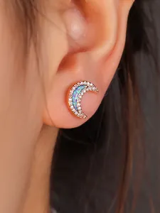 Macro view of crescent moon stud earrings in rose gold with opal stone and crystals